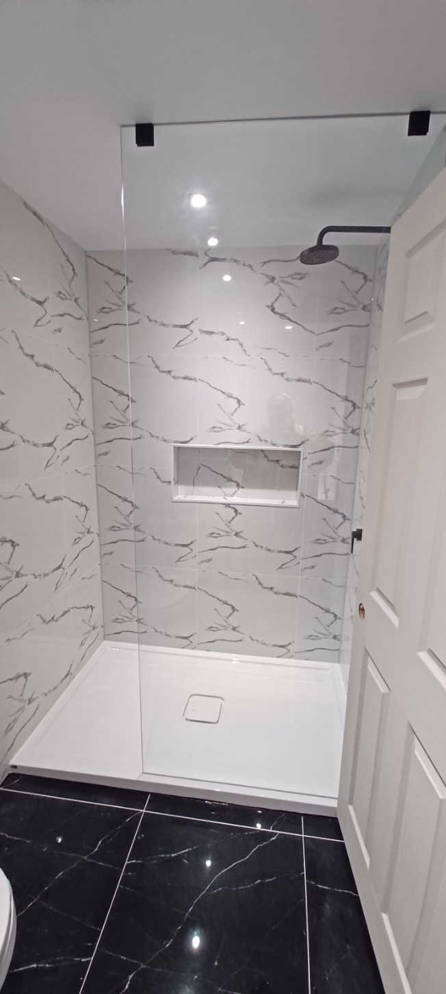 Finished walk-in shower with marble-look wall tile, glass panel and rainfall showerhead