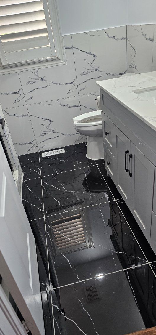 Finished washroom with polished black floor and marble-look wall tile
