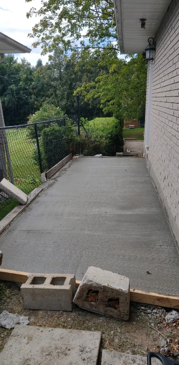 Newly poured concrete walkway along the side of a house
