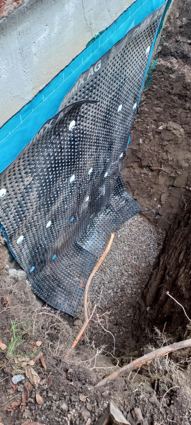 Black drainage membrane secured over a waterproof foundation wall