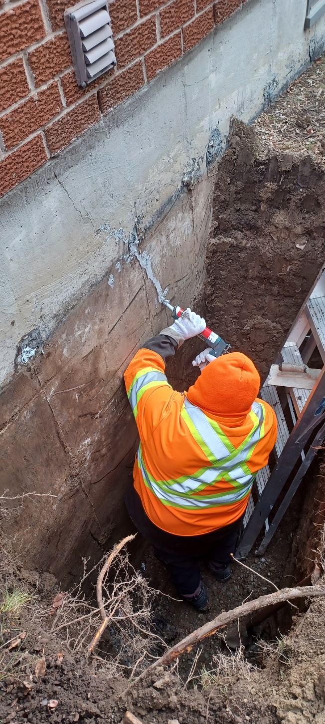 Worker preparing an excavated exterior foundation wall